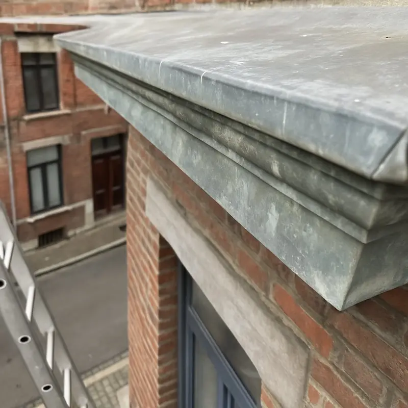 Corniche moulurée recouverte de zinc sur une façade en brique